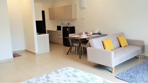 A modern apartment with a dining area, kitchenette, and a living room with a sofa and a coffee table. - ETM Midhill Comfy Studio Room (Genting Highlands)