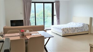 A hotel room with a bed, a TV, a dining table with chairs, and a window with curtains. - ETM Midhill Comfy Studio Room (Genting Highlands)