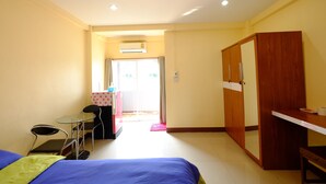 Une chambre d’hôtel avec un lit, un bureau, une chaise et une armoire.