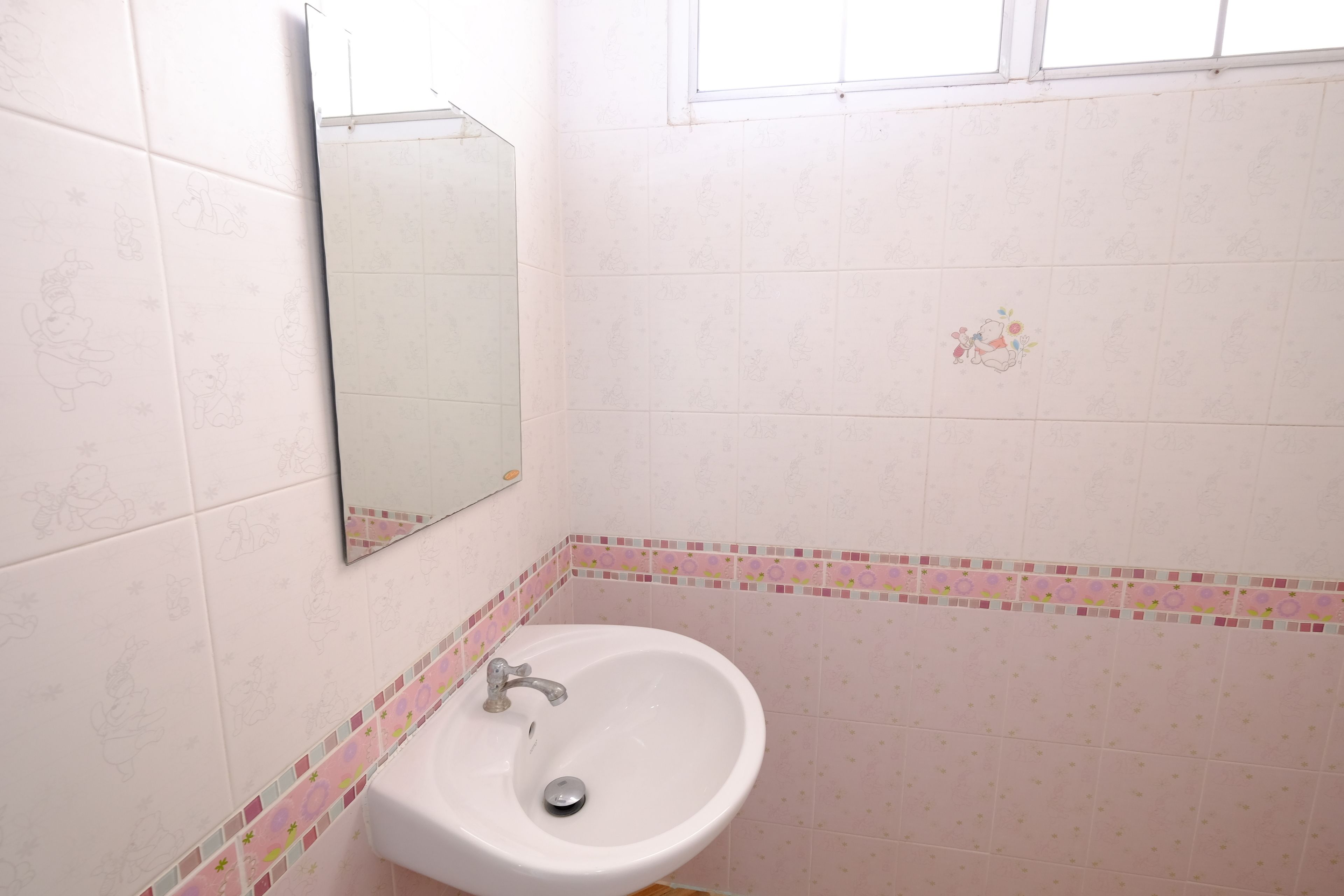 A bathroom with a white sink, a mirror, and patterned tiles.