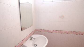 A bathroom with a white sink, a mirror, and patterned tiles.