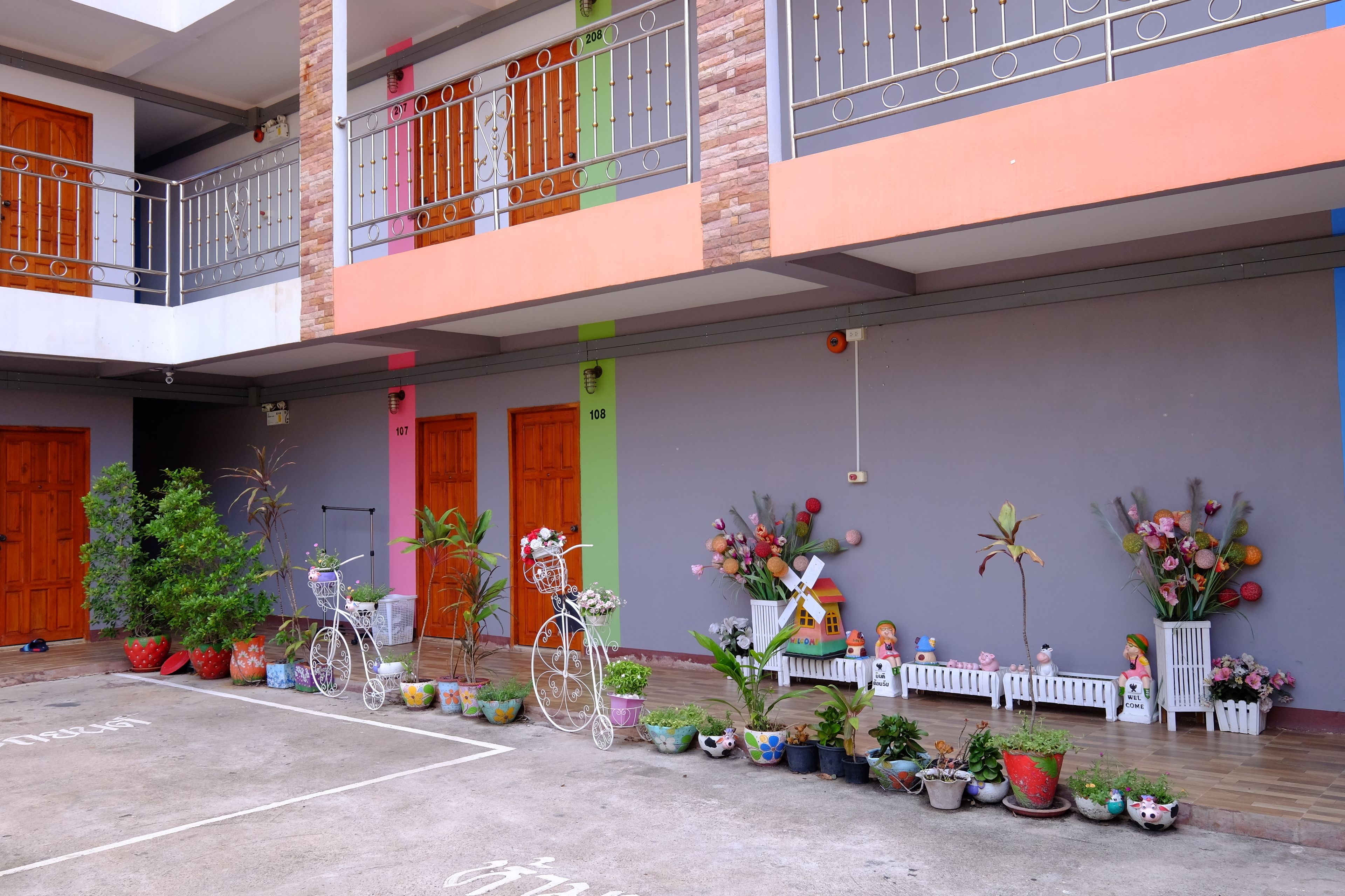 Un edificio de varios niveles con balcones, plantas en macetas y una bicicleta.