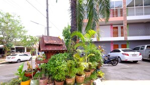 Une vue de rue avec une rangée de plantes en pot, une petite construction et des voitures garées.