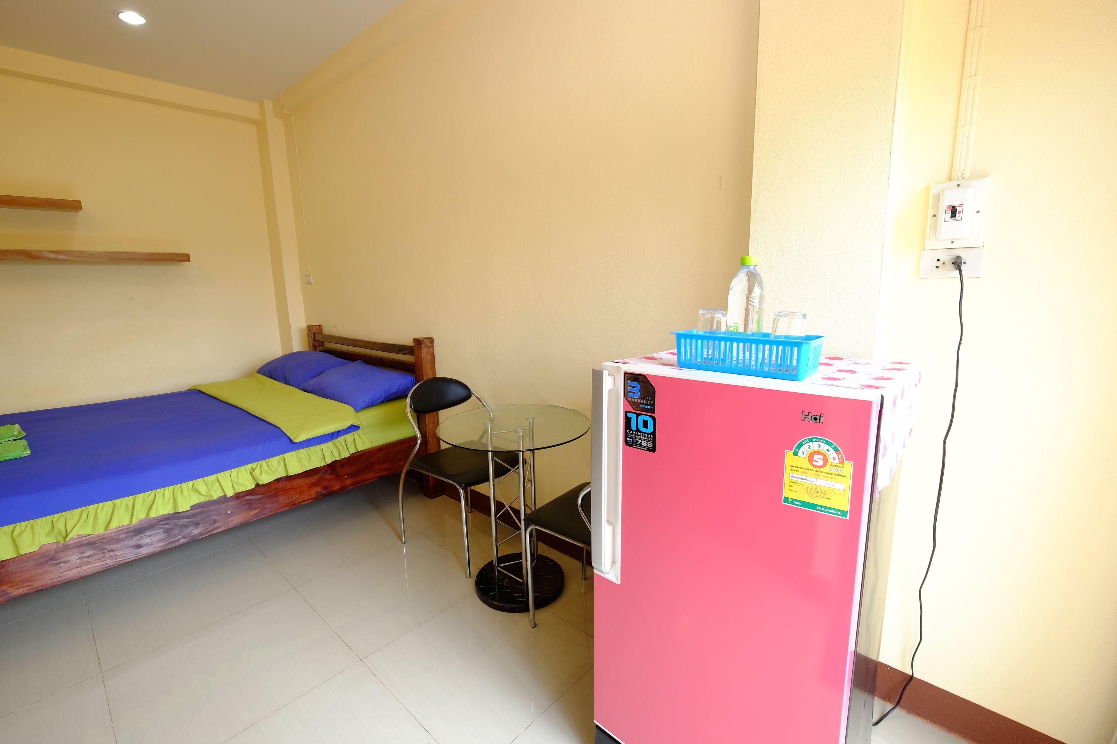 A small room with a bed, a table, and a refrigerator.