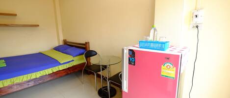 A small room with a bed, a table, and a refrigerator.