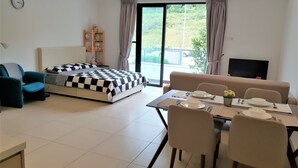 A modern living room with a bed, sofa, dining table, and a TV. - ETM Midhill Family Studio (Genting Highlands)
