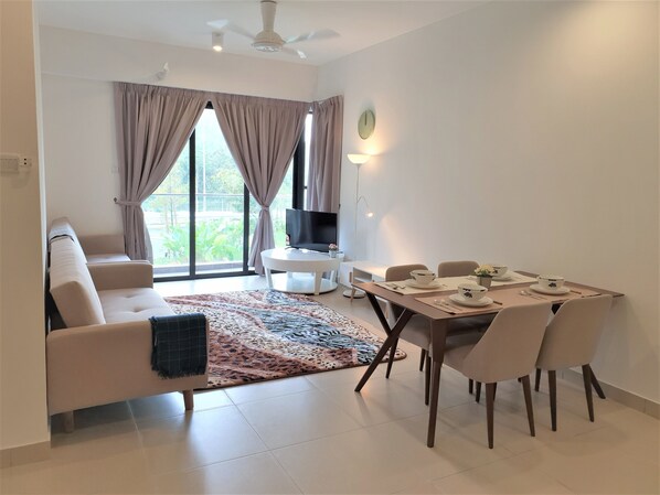 A modern living room with a sofa, TV, dining table, and chairs.