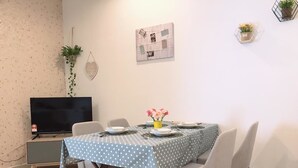 A dining area with a table set for four, chairs, a television, and a wall-mounted plant. - ETM Midhill Private Studio Room (Genting Highlands)