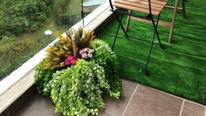 A balcony with a wooden table and chairs, a bottle of wine, and a glass. There is a view of a lush green landscape beyond the balcony. - ETM Midhill Genting Scenery Studio Room (Genting Highlands)