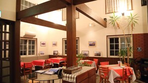 A restaurant with wooden beams, red and white checkered tablecloths, and potted plants. - Melange (Fujikawaguchiko)
