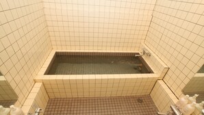 A bathroom with a bathtub, tiled walls, and a shower area. - Melange (Fujikawaguchiko)