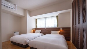 A hotel room with two beds, a window with curtains, a wall-mounted air conditioner, and a wardrobe with louvered doors. - Lieta Nakayama (Nago)