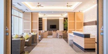 A hotel lobby with a reception desk, seating area, and a TV screen.