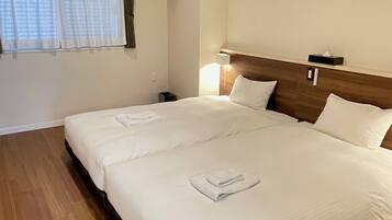 A hotel room with a large bed, a nightstand, a lamp, and an air conditioning unit.