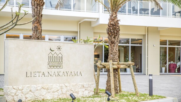 A sign for Lieta Nakayama with a modern building in the background. - Lieta Nakayama (Nago)