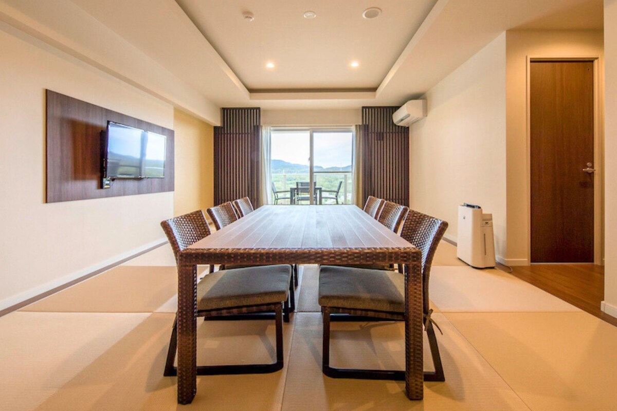 A conference room with a long table, chairs, a TV, and a door.
