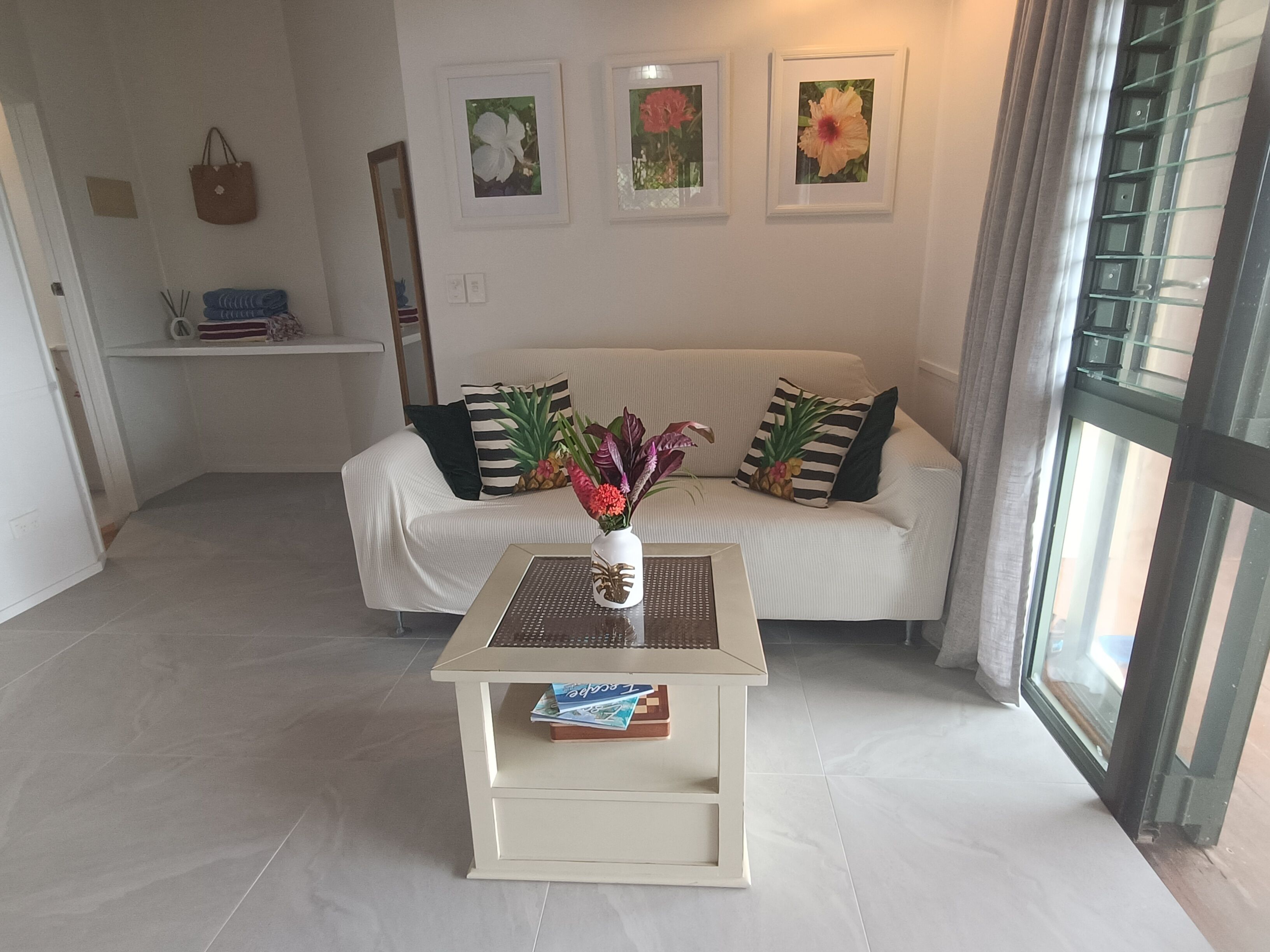 A modern living room with a white sofa, a small coffee table, and a large window.