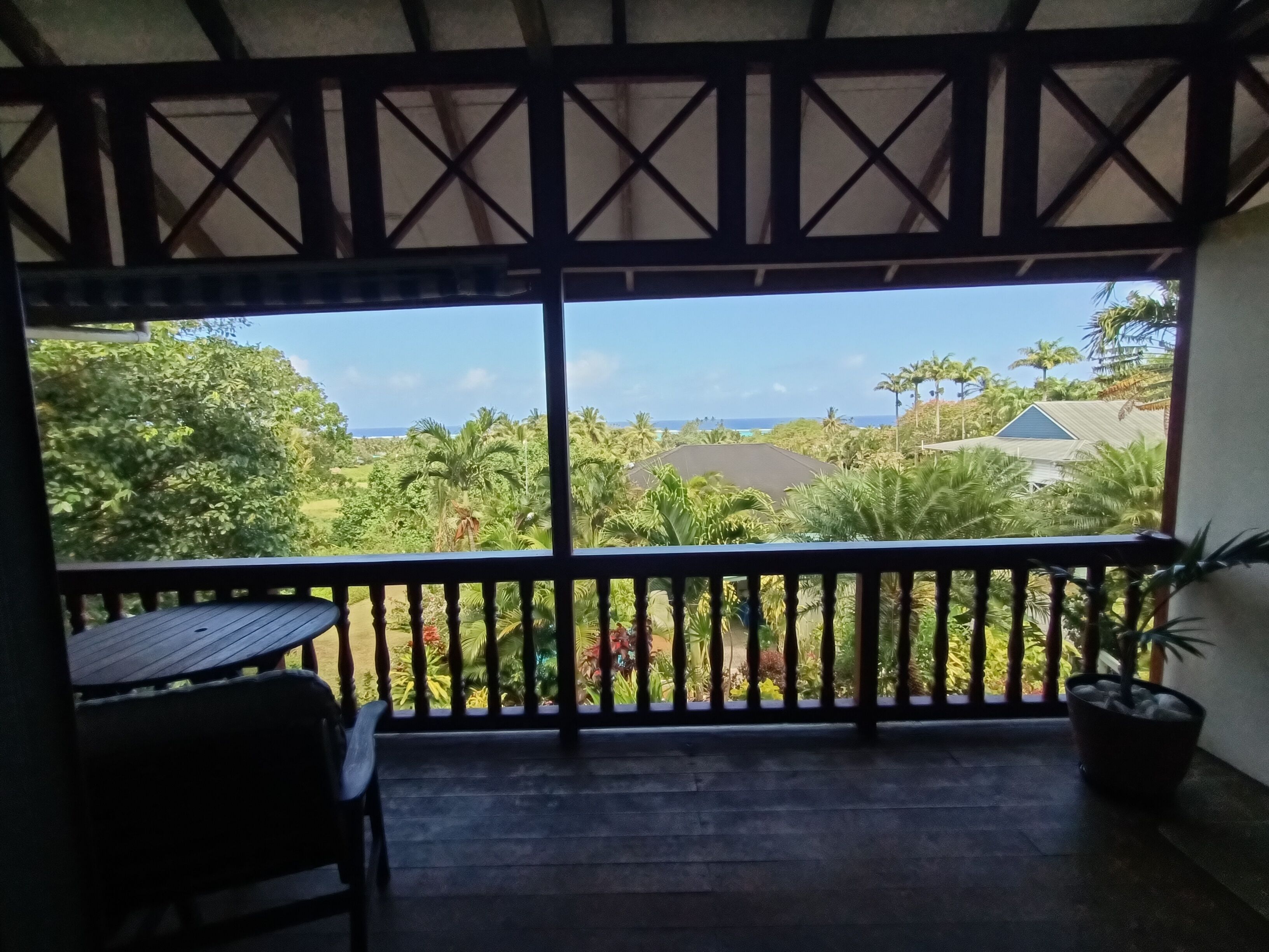 A balcony with a view of a lush garden and the ocean.