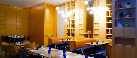 Una sala ristorante con diversi tavoli e posti a sedere, caratterizzata da stoviglie e tovaglioli blu.
