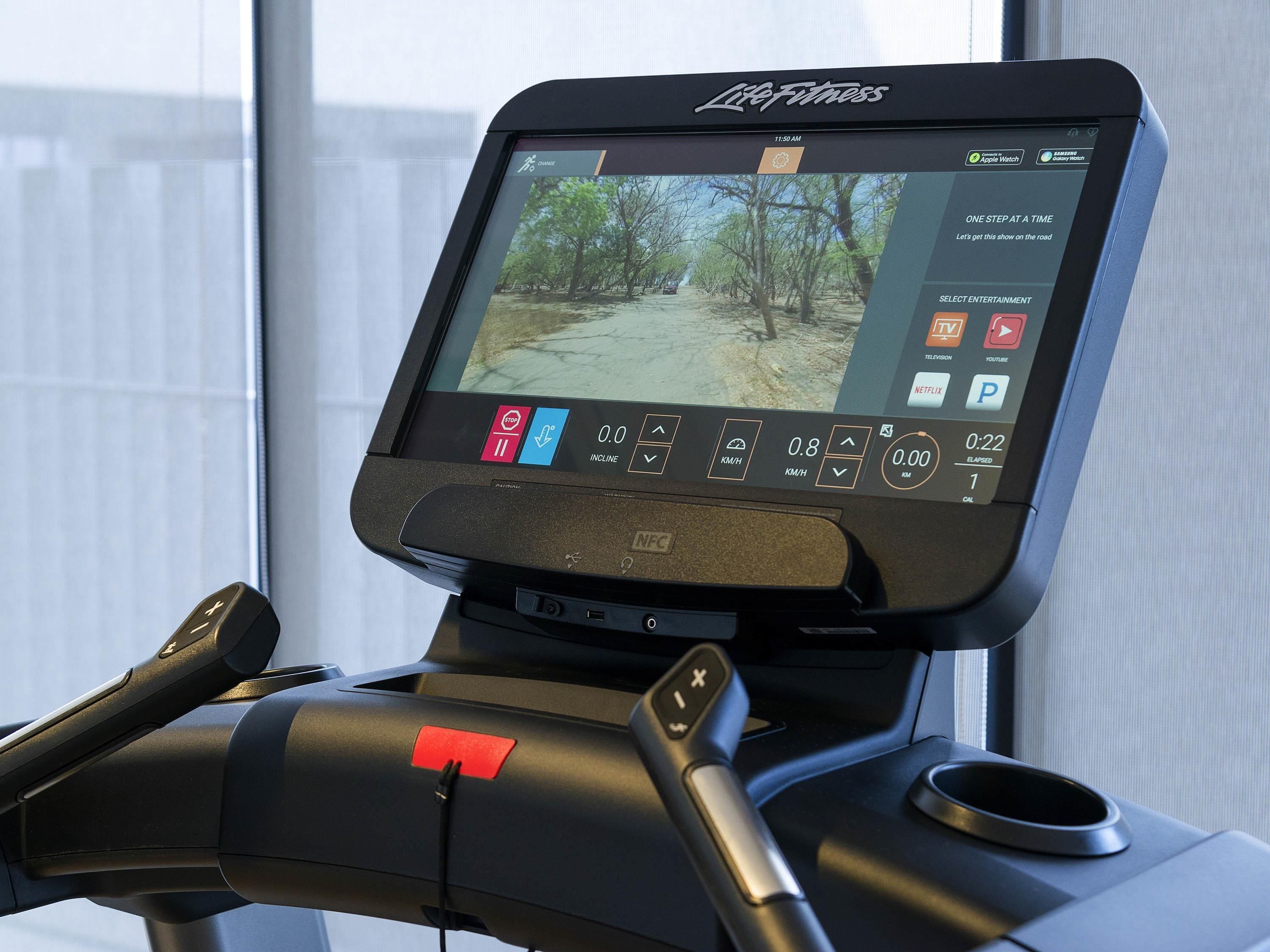 Ein Laufband mit digitaler Anzeige, Bedienfeld und einem roten Not-Aus-Knopf.