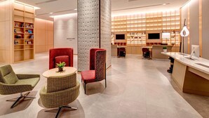 Un moderno vestíbulo de hotel con mostrador de recepción, zona de estar y una estantería.
