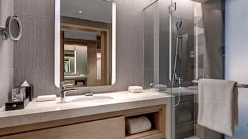 A modern bathroom with a large mirror, a shower, and a vanity with a towel rack.