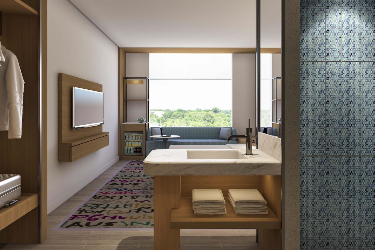 Un baño moderno con un espejo grande, un lavabo y un ventanal con vistas al verdor.