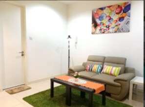 A living room with a sofa, a coffee table, a floor lamp, and a colorful artwork on the wall. - Bangsar Camelia Homestay KL (Kuala Lumpur)