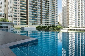 A modern high-rise building with a large swimming pool in the foreground. - Bangsar Camelia Homestay KL (Kuala Lumpur)