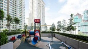 A playground with slides and swings, surrounded by tall buildings and greenery. - Bangsar Camelia Homestay KL (Kuala Lumpur)