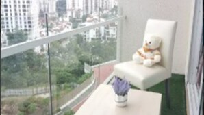 A balcony with a white chair and a teddy bear, overlooking a cityscape. - Bangsar Camelia Homestay KL (Kuala Lumpur)