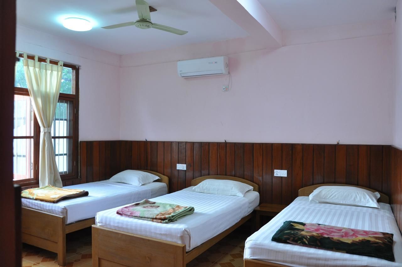 Een kamer met drie houten bedden, een plafondventilator en een airconditioning.