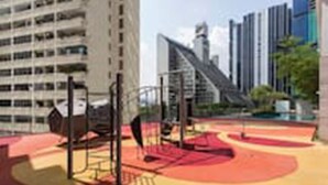 A playground with red and yellow equipment, surrounded by tall buildings. - Pipit Homestay at Element Ampang (Kuala Lumpur)