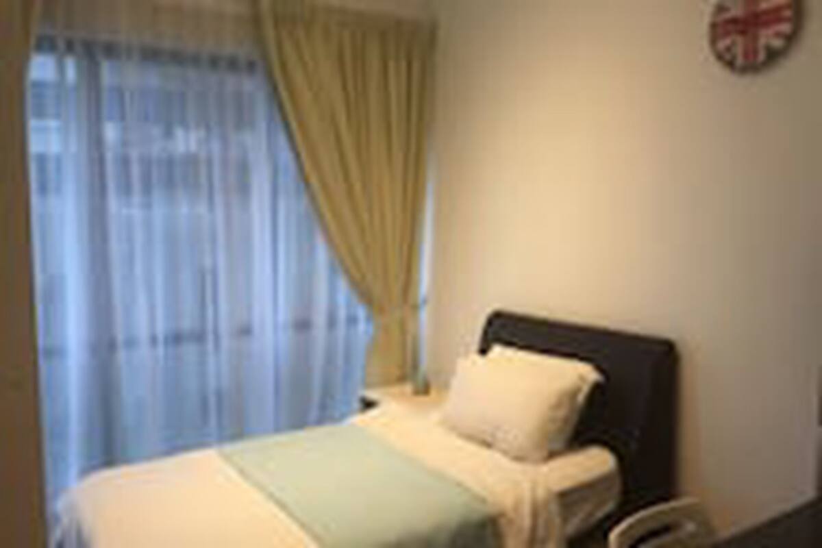 Ein Zimmer mit einem Bett, einem Vorhangfenster und einer Wanduhr.