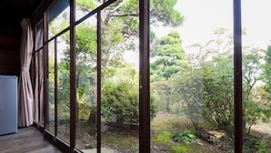 Una habitación con amplios ventanales que dan a un jardín con diversos árboles y plantas.