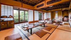 Una habitación japonesa tradicional con suelo de tatami, puertas correderas y techo bajo con vigas a la vista.