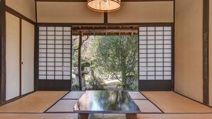 Una habitación japonesa tradicional con suelo de tatami, paneles shoji y vistas a un jardín.