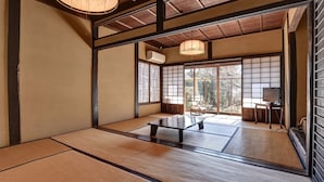 Una habitación japonesa tradicional con suelo de tatami, puertas correderas y vistas al exterior.