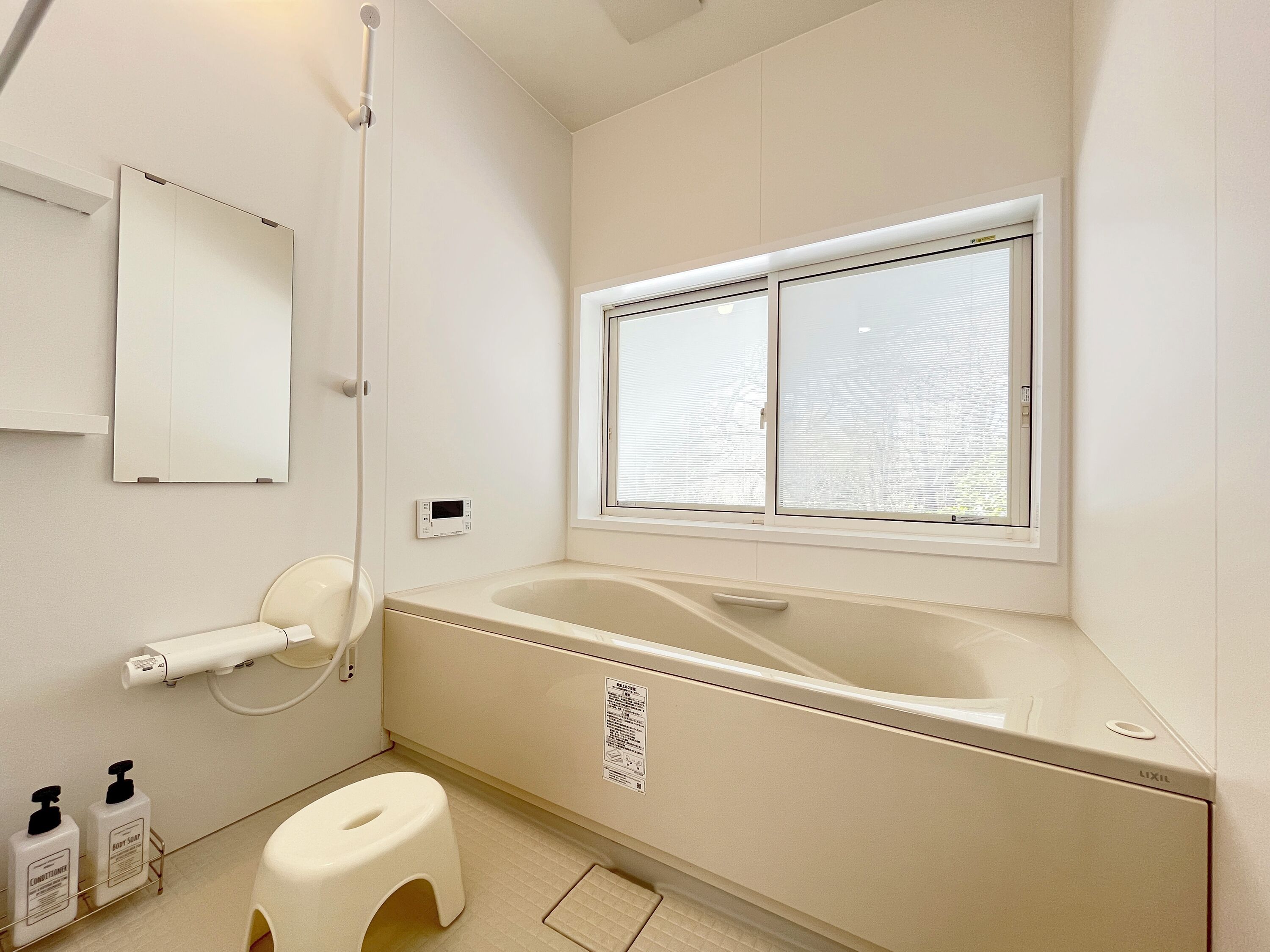 A bathroom with a bathtub, a toilet, a shower, a window, and a mirror.