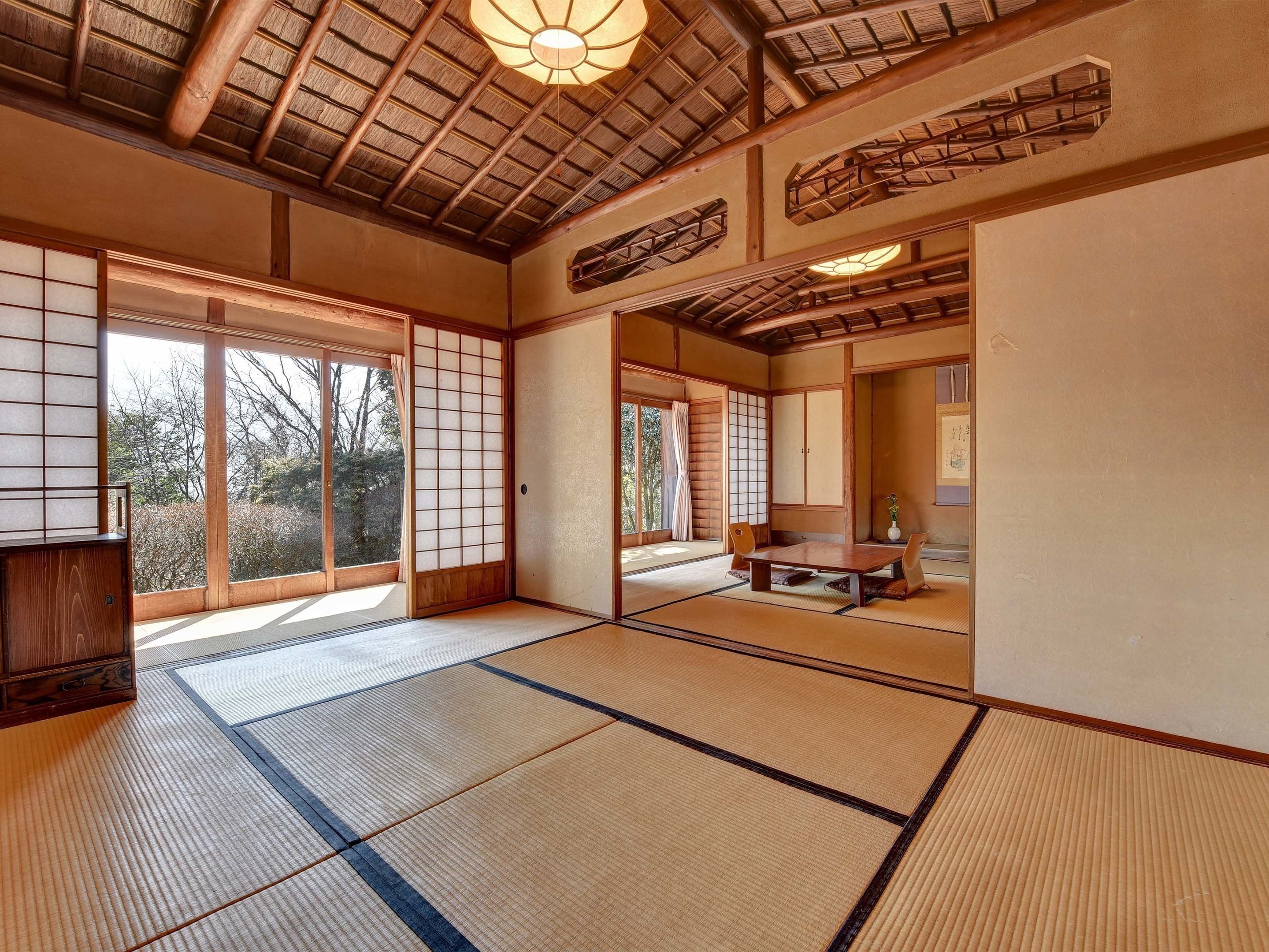 A traditional Japanese room with tatami flooring, sliding doors, and a thatched roof.