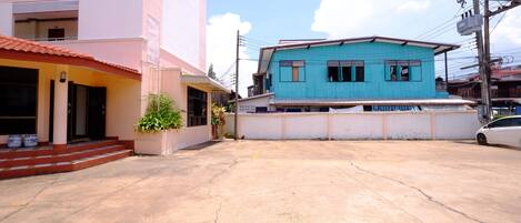 A building with a pink facade and a blue one-story structure in the background.