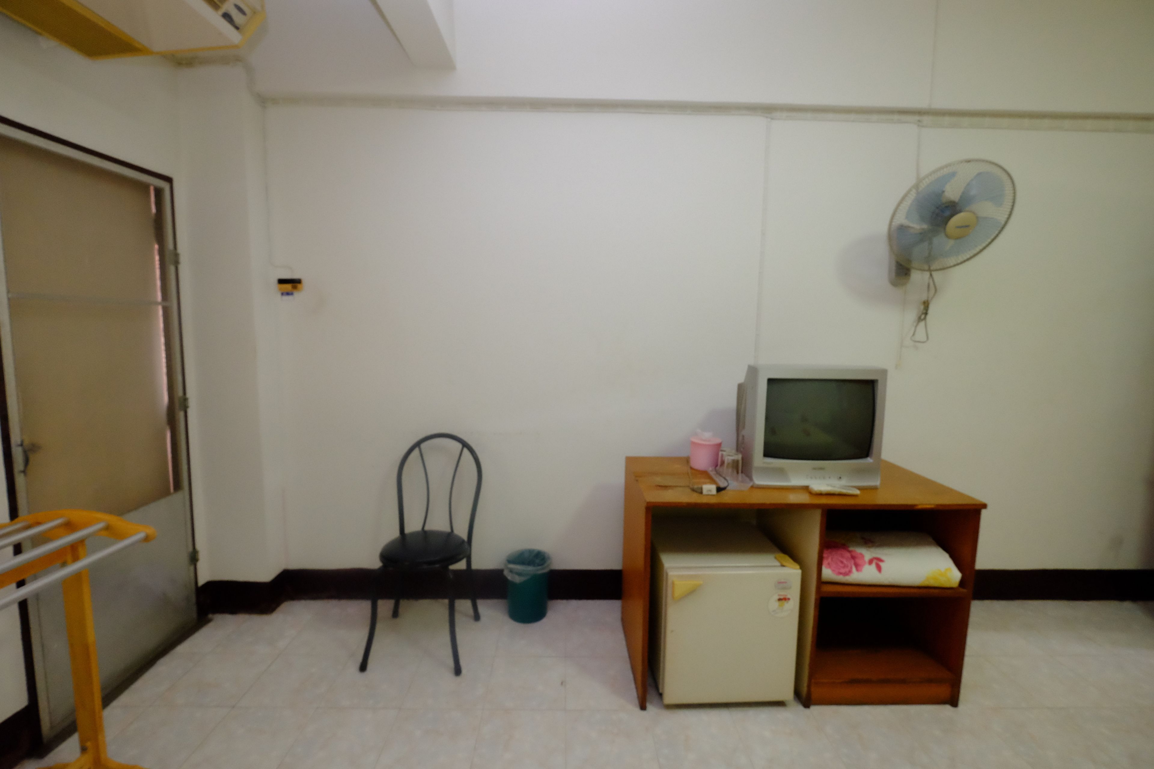 A small room with a desk, chair, and a television.