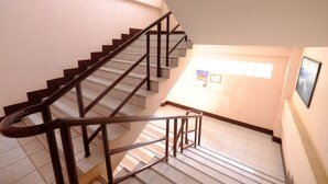 Una escalera con barandilla que conduce a una plataforma con un cuadro enmarco y una ventana.