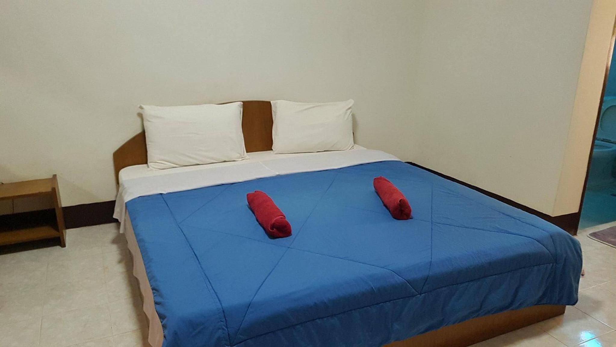 A standard hotel room with a bed, pillows, and a blue bedspread.