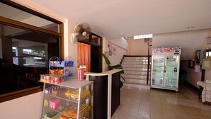 Zona de recepción con mostrador, ventilador, refrigerador y vitrina de vidrio con aperitivos.