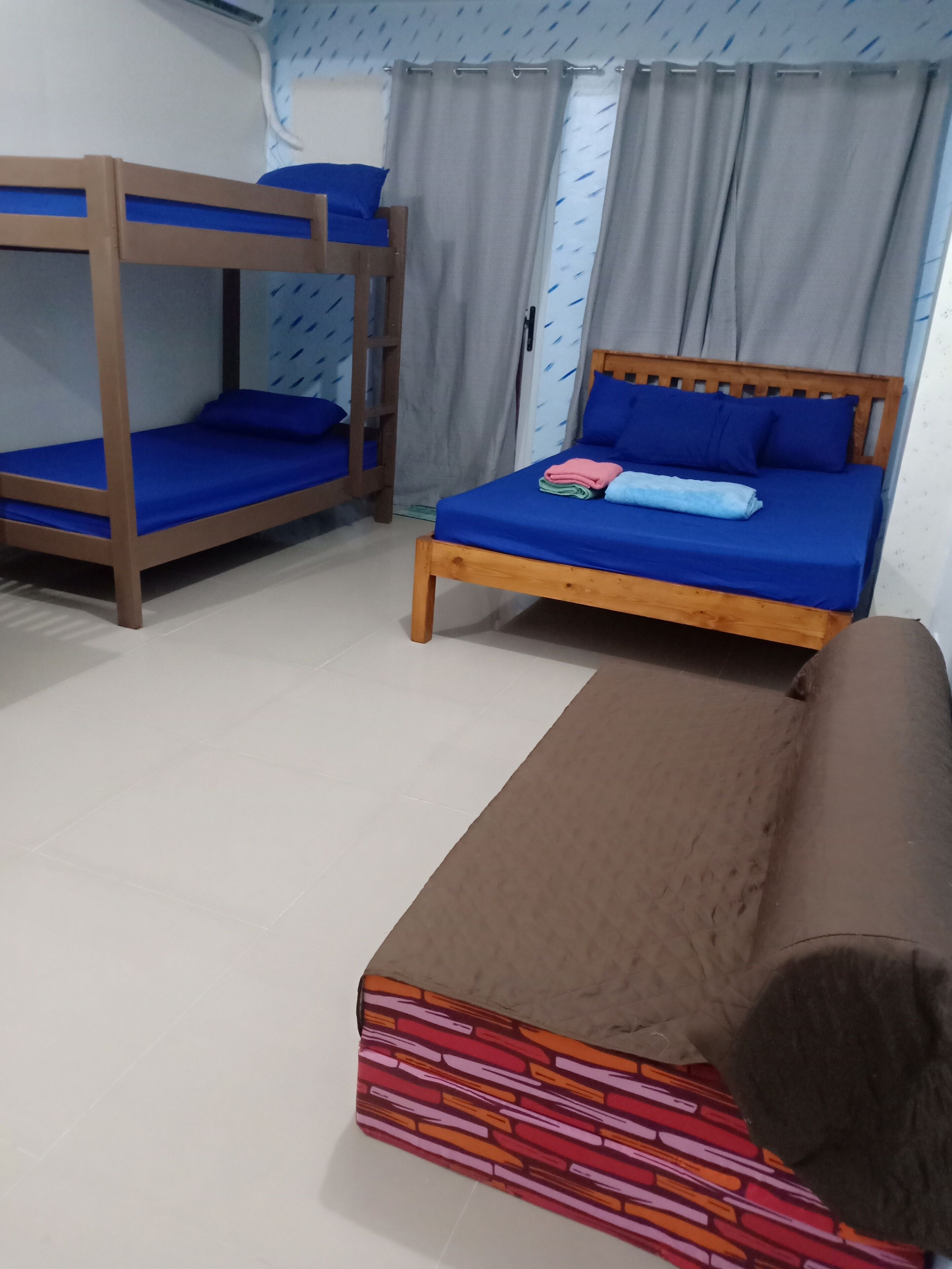 A room with a bunk bed, a single bed, and a sofa.