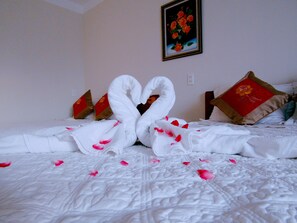 A bed with a swan-shaped arrangement of towels and rose petals. - Hoang Dat hotel (Dong Thuan)