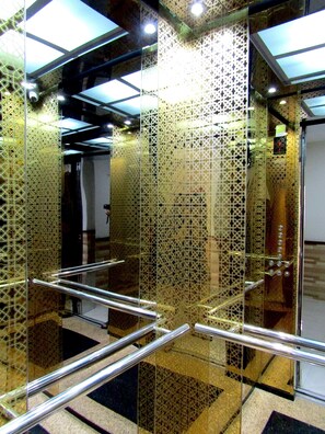 An elevator with a geometric patterned wall and metal handrails. - Hoang Dat hotel (Dong Thuan)