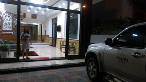 Un edificio moderno con ingresso in vetro, un'auto bianca parcheggiata all'esterno e un estintore ben visibile.
