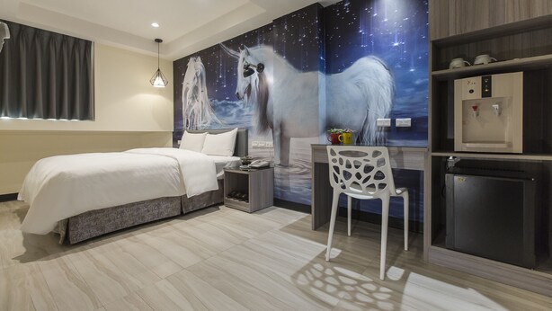 Une chambre d’hôtel moderne équipée d’un lit, d’un bureau et d’un distributeur d’eau.